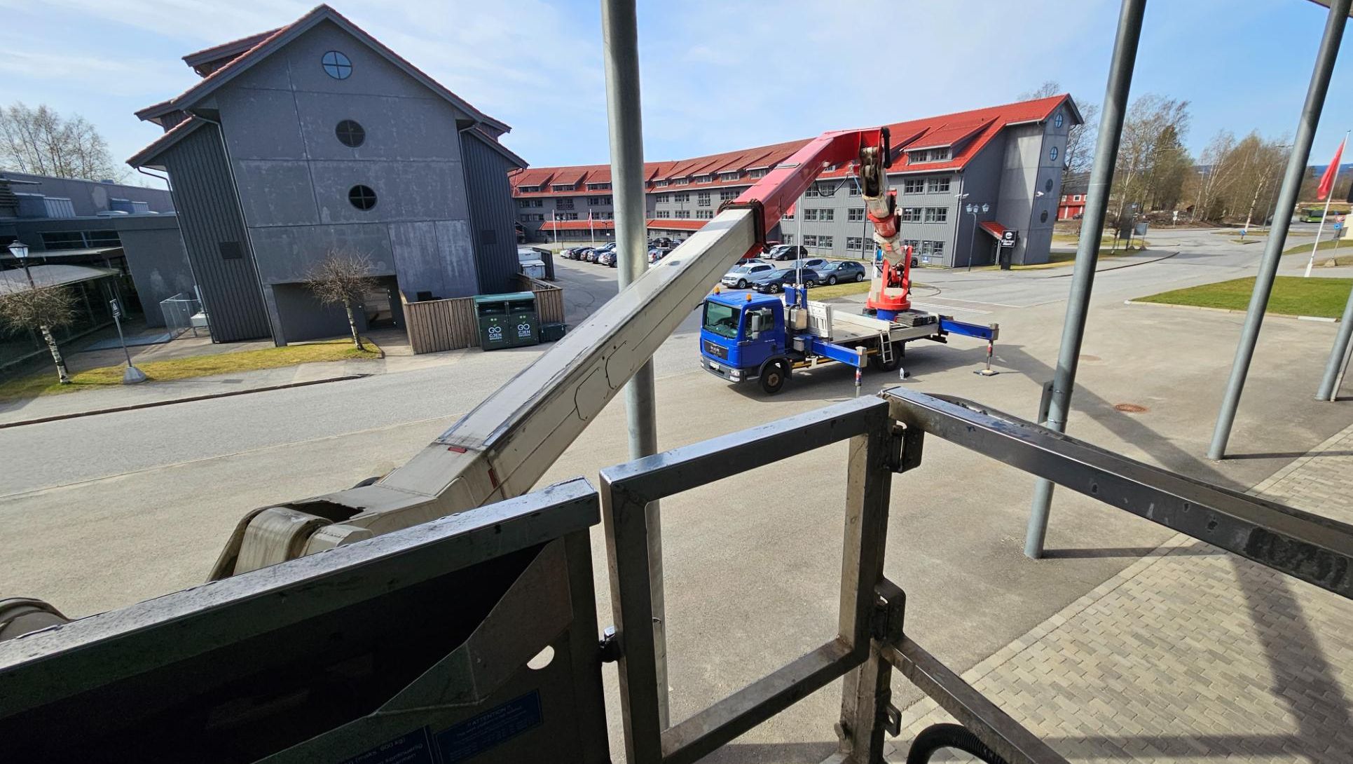 Liftbil fra Ryggelift Havn sett fra arbeidskurven mens bomarmen er hevet mot bygg. Viser arbeid i høyden ved næringsområde.